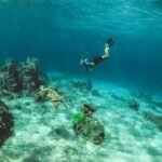 man in blue shorts diving on water