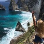 a woman standing on top of a cliff next to the ocean